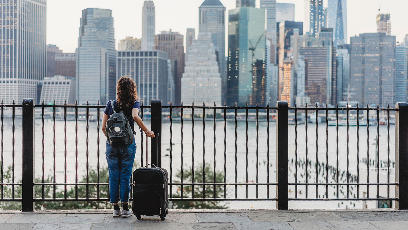 woman with luggage looking at NYC buildings