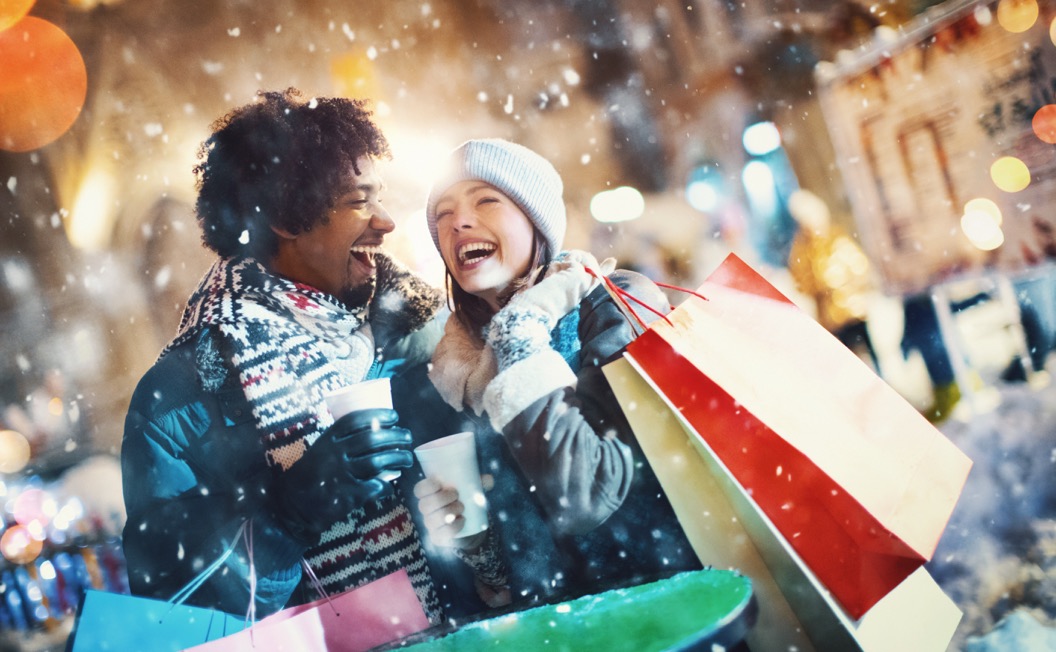 A couple laughs carrying shopping bags during the holiday season